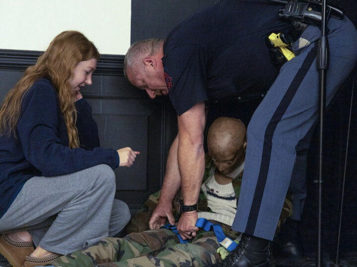 Police officer demonstrating how to save a child with college student